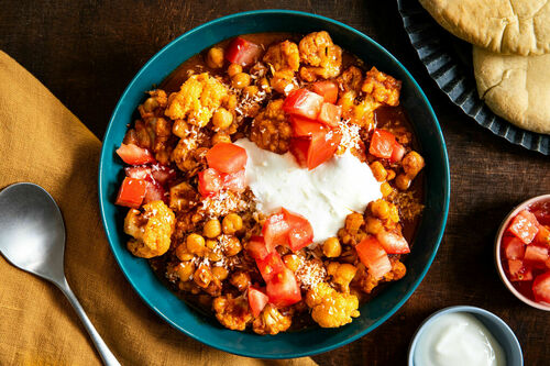 Kichererbsen-Blumenkohl-Curry serviert mit Joghurt und warmem Pitabrot