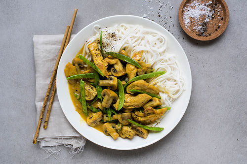 Thailändische Hähnchenstreifen mit Reisnudeln in gelber Currysauce