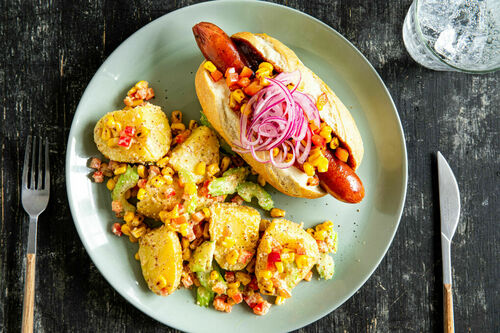 Hotdog mit Geflügelwurst und Mais-Salsa dazu Kartoffel-Erdnuss-Salat