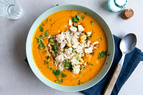 Masala-Hähnchensuppe mit Reis garniert mit Erdnüssen und Koriander