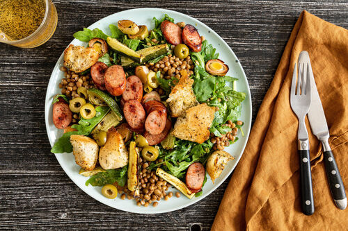 Rindswurst und Zucchini-Lauch-Gemüse auf Rucola-Linsen-Salat mit Croûtons
