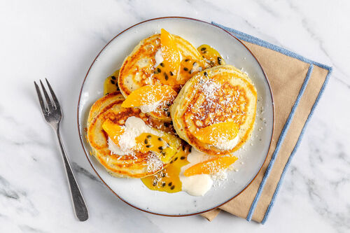 Passionsfrucht-Pancakes serviert mit Joghurt und Kokosraspeln