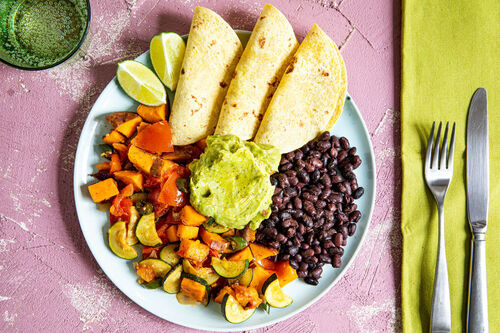 Mexikanische Gemüsepfanne dazu schwarze Bohnen, Guacamole und Tortillas