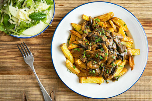 Würzige Pilzpfanne auf Ofenpommes dazu Salat mit Apfel und Käse