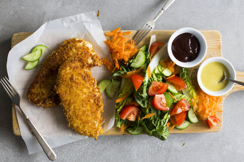 Hähnchen in Cornflakeskruste auf buntem Karotten-Salat