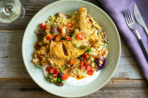 Hähnchenschenkel mit Blumenkohl garniert mit Joghurt und Tomate