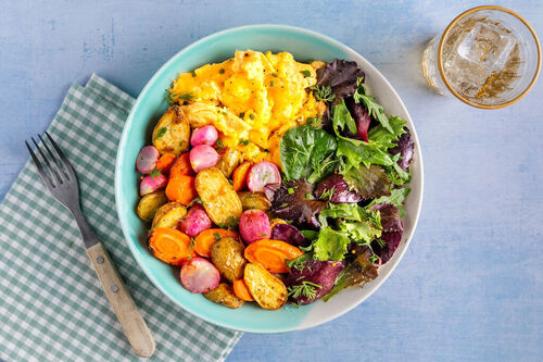 Frühstücksbowl mit Käse-Rührei und Ofengemüse, dazu Salat mit Kräutern