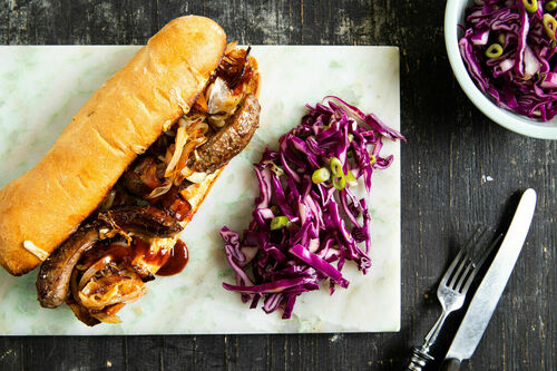 Sandwich mit Rindswurst und Käse mit Rotkohlsalat und gerösteten Zwiebeln