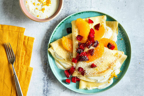 Palatschinken mit Orangen und Pflaumen verfeinert mit Joghurt und Puderzucker