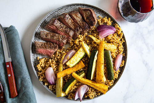 Rindersteak und buntes Ofengemüse an würzigem Perlencouscous