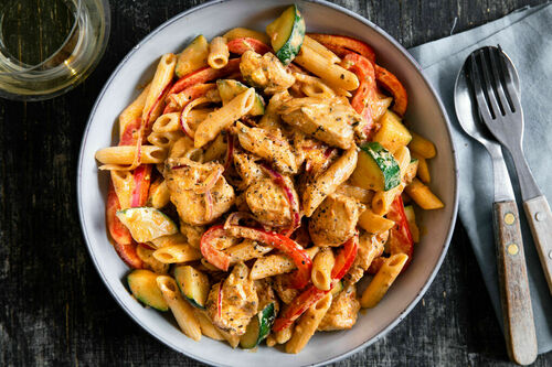 Penne mit zarten Hähnchenwürfeln in cremiger Pesto-Sauce mit Gemüse