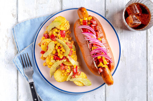 Hotdog mit Geflügelwurst und Mais-Salsa dazu Kartoffel-Erdnuss-Salat