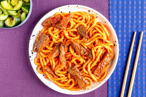 Bio-Rindfleisch-Nudelpfanne mit Austernpilzen und Gurkensalat