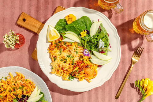 Scharfe Käsespätzle mit Kimchi und Spiegelei an feinem Salat mit Apfel und Blüten