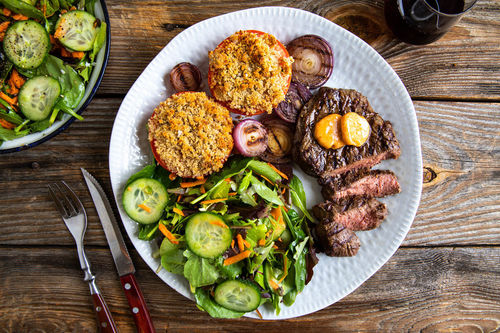 Steak mit BBQ-Butter und Röstzwiebeln dazu Tomaten mit Bröselhaube und Salat