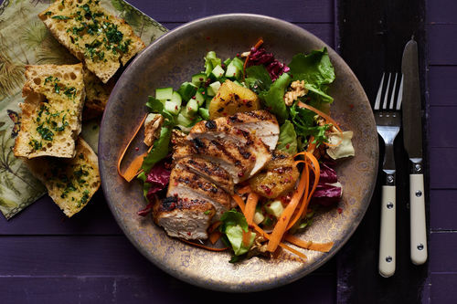 Zartes Hähnchen mit Orange auf buntem Salat mit Kräuterbaguette