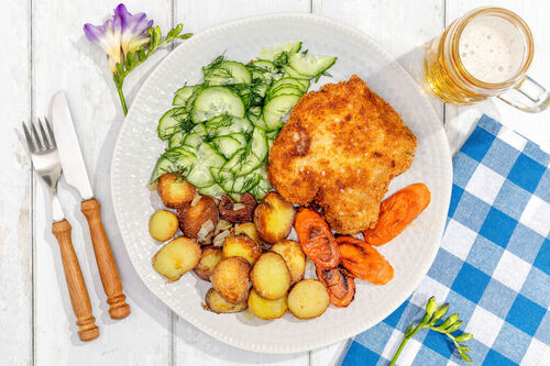 Paniertes Schweinekotelett mit Bratkartoffeln dazu Karotten und Gurkensalat mit Dill