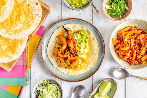 Paprikahähnchen in Cheddar-Wraps mit Guacamole, Salat und Limettenspalten