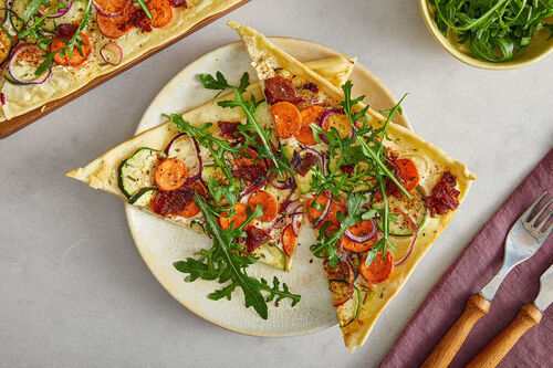 Veganer Karotten-Zucchini-Flammkuchen mit getrockneten Tomaten und Rucola