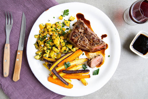Zartes Rindersteak mit würziger Sauce mit Rissolée-Kartoffeln und bunten Karotten
