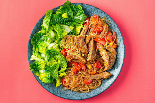 Tomatige Schweinefleisch-Pfanne mit Glasnudeln und Eisbergsalat