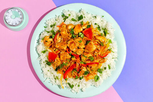 Satay-Hähnchenpfanne mit Koriander serviert auf duftendem Basmatireis