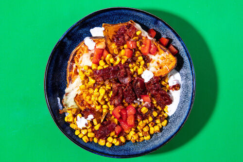 Prall gefüllte Süßkartoffel mit Bacon dazu gebratener Mais und frische Tomaten