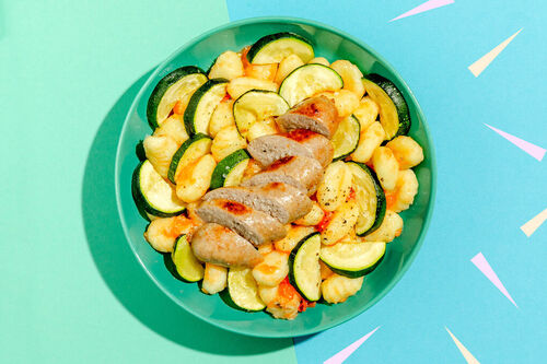 Würzige Schweinswurst auf Gnocchi mit Zucchini und Tomaten