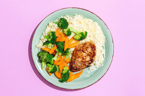 Schweinesteak mit buntem Gemüse serviert auf feinem Couscous