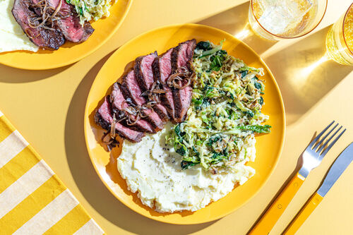 Rindersteak an cremigem Wirsing-Spinat serviert mit Kartoffelpüree und Schalotten