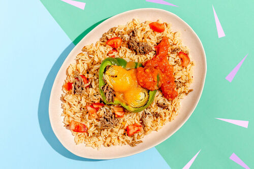 Gefüllte Paprika mit Rinderhack und Käse serviert auf buntem Jasminreis