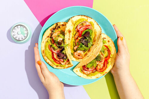 Bunte Garnelen-Tacos mit Guacamole mit frischen Tomaten und eingelegten Zwiebeln