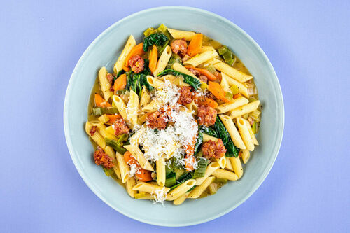 Schweinswurst-Pasta mit buntem Gemüse und geriebenem Käse