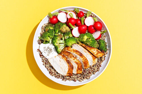 Hähnchen-Quinoa-Bowl mit buntem Gemüse serviert mit Minzjoghurt