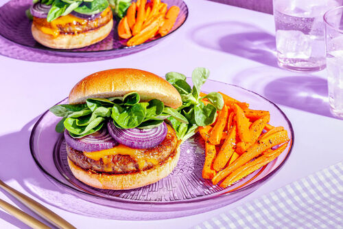 Saftiger Bio-Cheeseburger mit Zwiebeln dazu geröstete Karotten und Feldsalat
