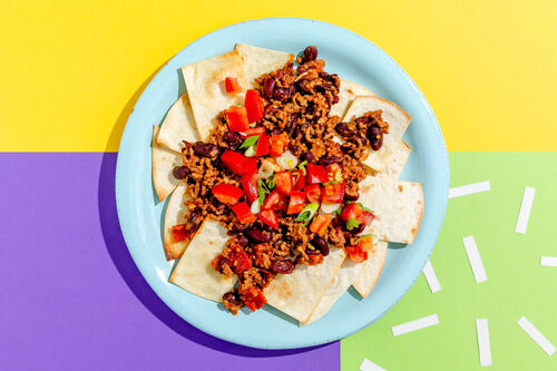High-Protein-Nachos mit Chili con Carne garniert mit Lauchzwiebeln und Tomaten