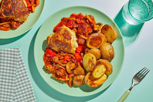 Hähnchenschenkel mit Ofenkartoffeln auf Paprika-Tomatensauce mit Schweinswurst