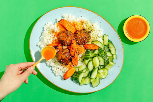 Koreanische Fleischbällchen auf Sushireis mit Karotten, Chilisauce und Gurkensalat