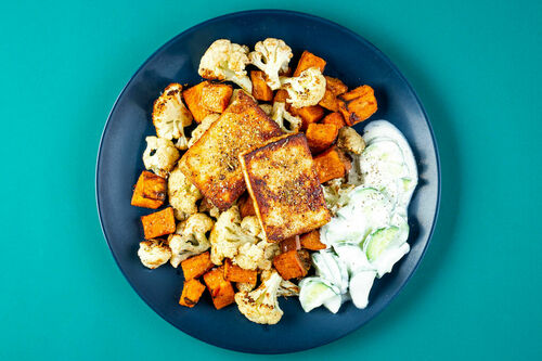 Würziger Paneer an aromatischem Röstgemüse serviert mit frischem Gurkensalat