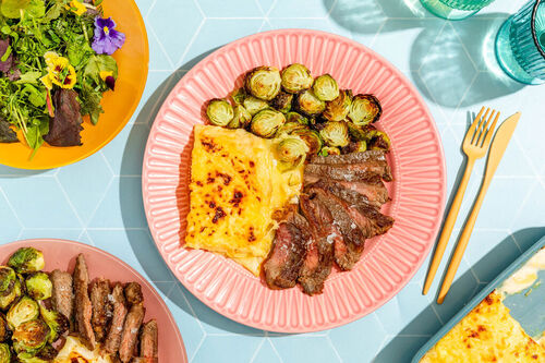 Rindersteak an Béchamel-Kartoffelgratin serviert mit geröstetem Rosenkohl und Salat
