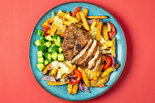 Schweinesteak und überbackene Pommes nach griechischer Art, dazu Gurkensalat