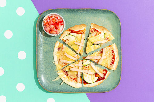 Tortilla-BBQ-Pizza mit Hähnchen und Zucchini, darauf Tomatentopping