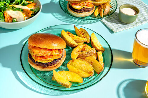 Pikanter Bio-Burger mit Kimchi und Birne serviert an Kartoffelspalten und Salat