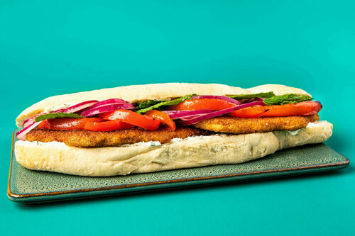 Veggieschnitzel-Baguette mit Minzjoghurt und eingelegten Zwiebeln auf Paprika