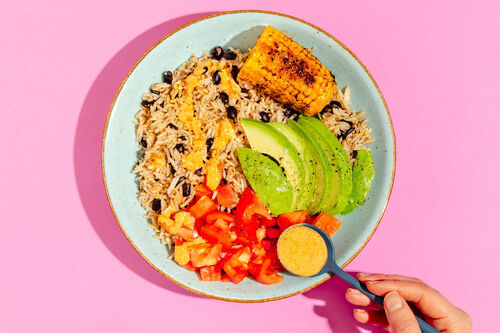 Cajun-Reisbowl mit Avocado und Mais garniert mit frischer Tomatensalsa