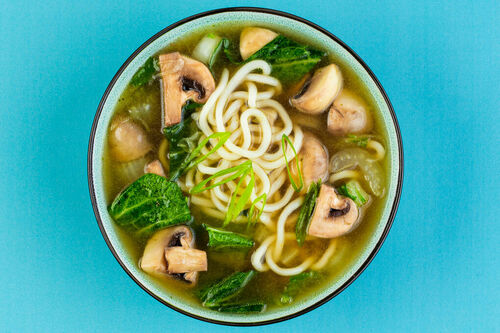 Udon-Suppe mit Pilzen und Pak Choi garniert mit Lauchzwiebeln