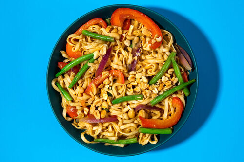 Asianudeln mit Paprika und grünen Bohnen in Ingwer-Soja-Sauce, garniert mit Erdnüssen