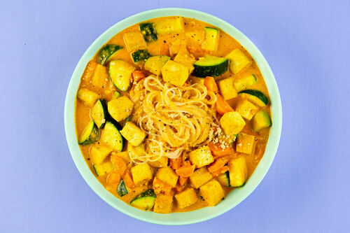 Curry-Erdnuss-Suppe mit gebratenem Tofu mit buntem Gemüse und Glasnudeln