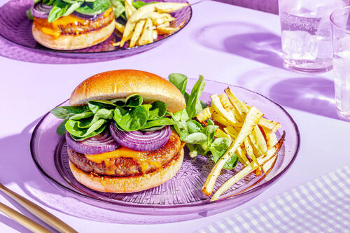 Saftiger Bio-Cheeseburger mit Zwiebeln dazu geröstete Pastinaken und Feldsalat