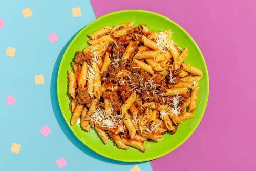 Herzhafte Paprika-Puten-Bolognese mit Penne und geriebenem Käse